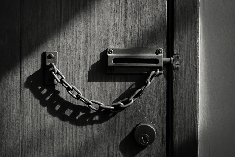 Porte fermée avec chaîne de sécurité, lumière du jour, textures visibles.